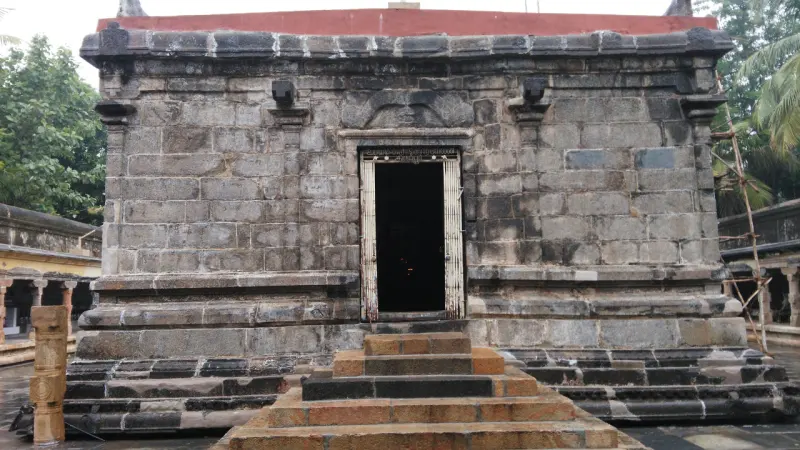 A shrine built of large stone blocks, with a single dark doorway and steps leading up.