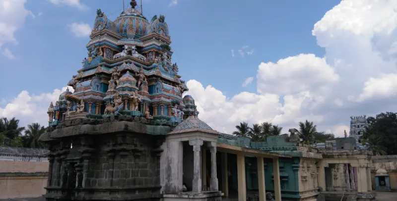 Painted shrine tower above a dark stone wall, with a pillared corridor beside it
