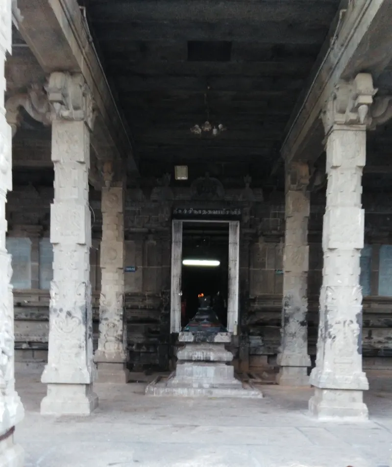 Long hall of carved stone pillars with a stepped pedestal before a lit doorway