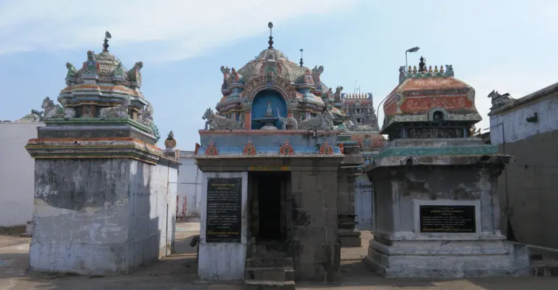 Three small stone shrines with colourful towers side by side