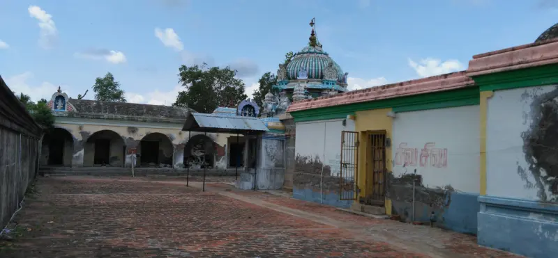 A brick-paved courtyard with a pillared corridor on the left and the shrine dome behind