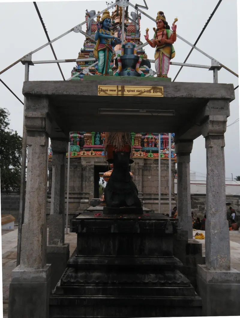 Black Nandi bull under a pavilion, with deity figures above and tower behind