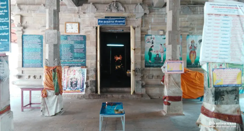 Open sanctum doorway under a Tamil name board, with paintings on the wall beside it