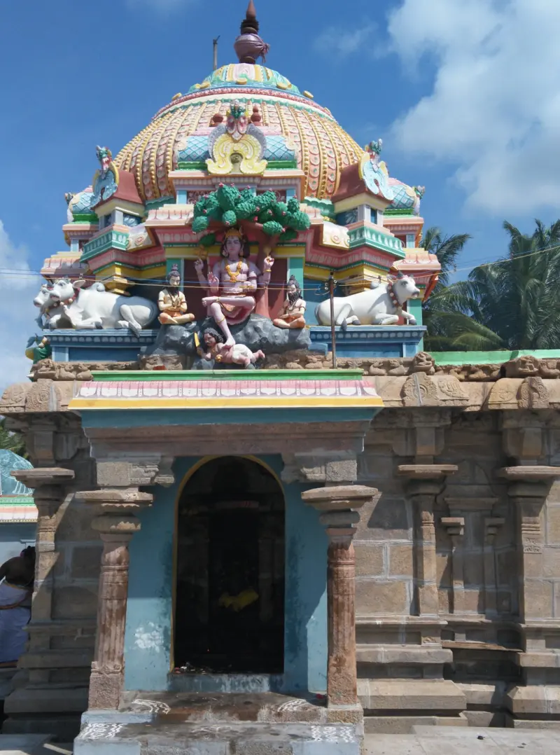 A shrine with a coloured dome and stucco figures above its arched, open doorway