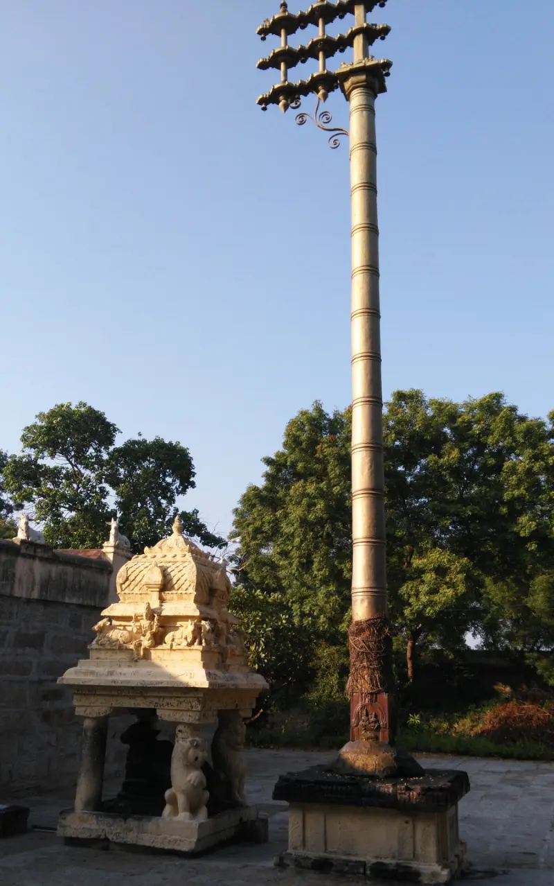 A towering brass flagstaff with lamps at its top