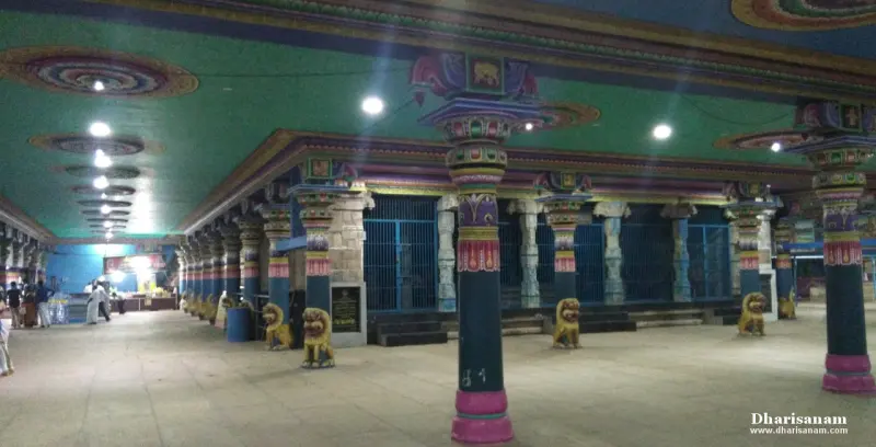 A wide hall with painted pillars, a green ceiling and golden lion statues along the aisle