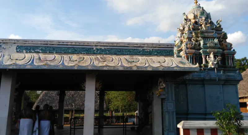 An open pillared hall with a carved frieze on its roof edge; a tower with sculptures rises on the right.