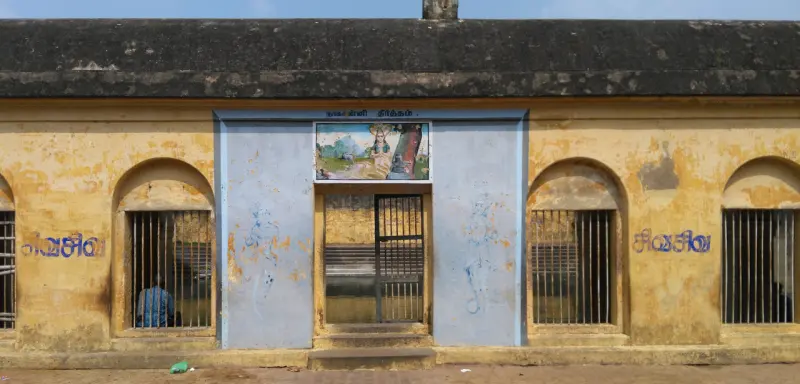 Yellow wall with barred windows and a mural gate