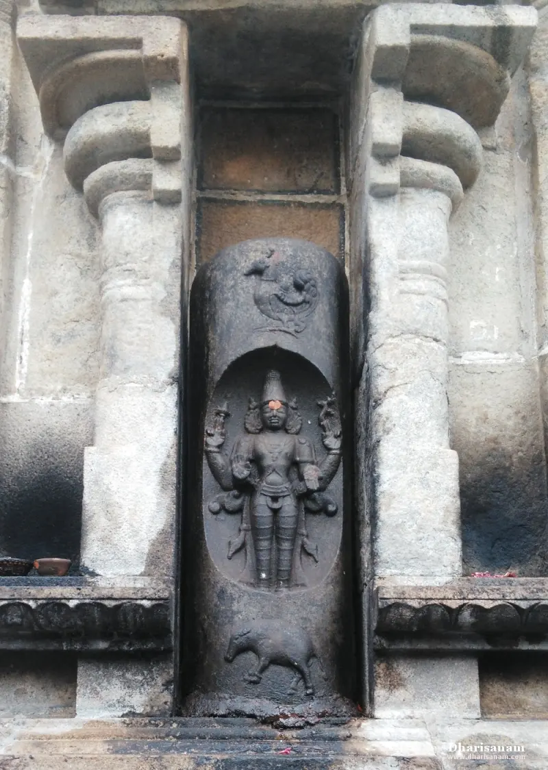 A relief of a standing four-armed figure in an oval recess, with a bird carved above and an animal below