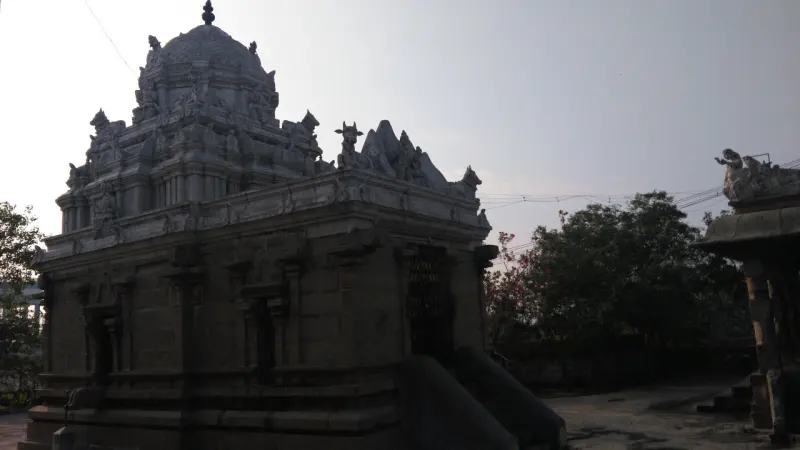A stone shrine with a domed tower and Nandi figures on the parapet, in dim evening light