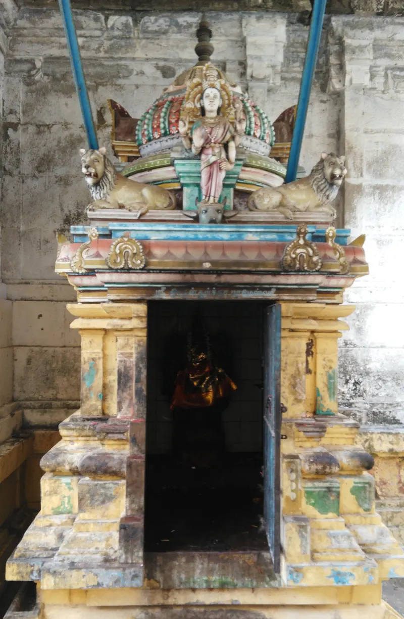 A small shrine with a goddess figure and two lions on its roof, and a dark doorway