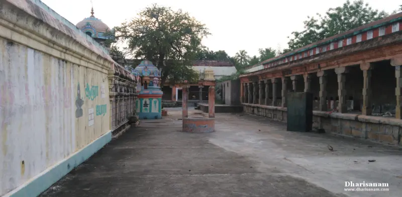 A wide paved corridor with a pillared hall on the right and a painted shrine at its far end.