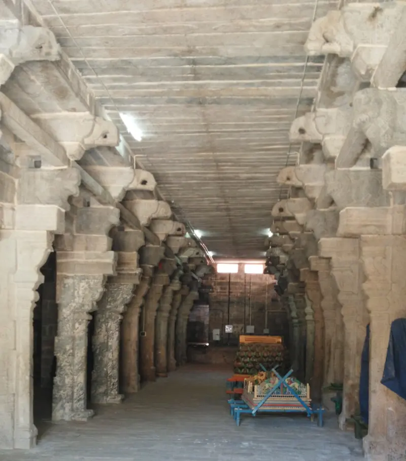 A long stone hall with carved pillars on both sides and a wooden stand at the far end.