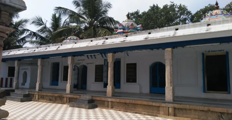 White pillared corridor with blue doors and a tiled courtyard