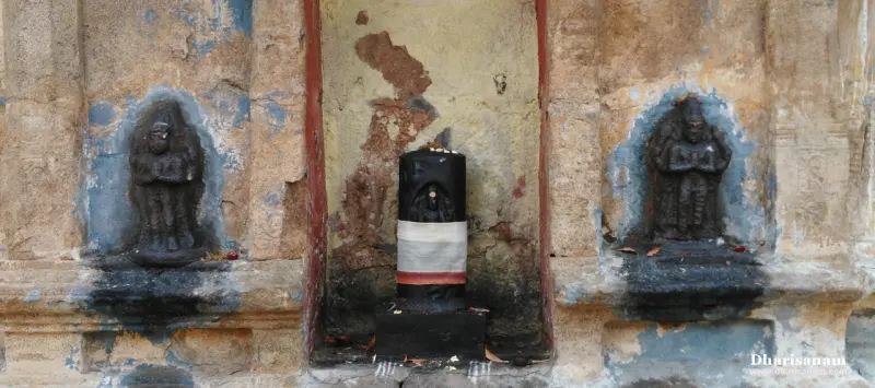 A cloth-wrapped lingam between standing idols on a weathered wall