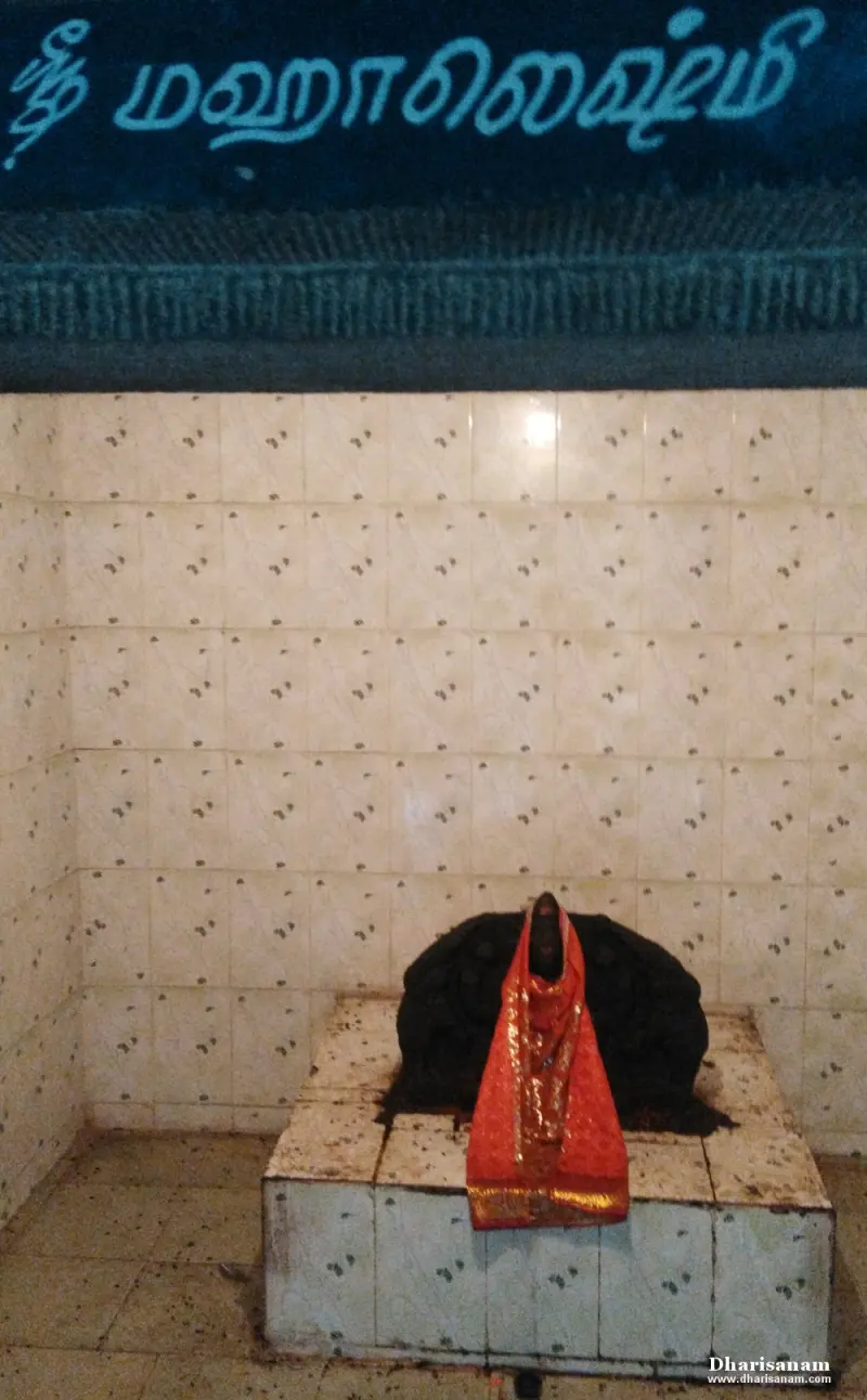 Dark idol with a red cloth under a Tamil name board