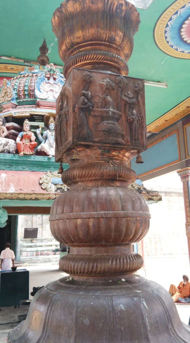 Carved bronze column with bells under a green ceiling