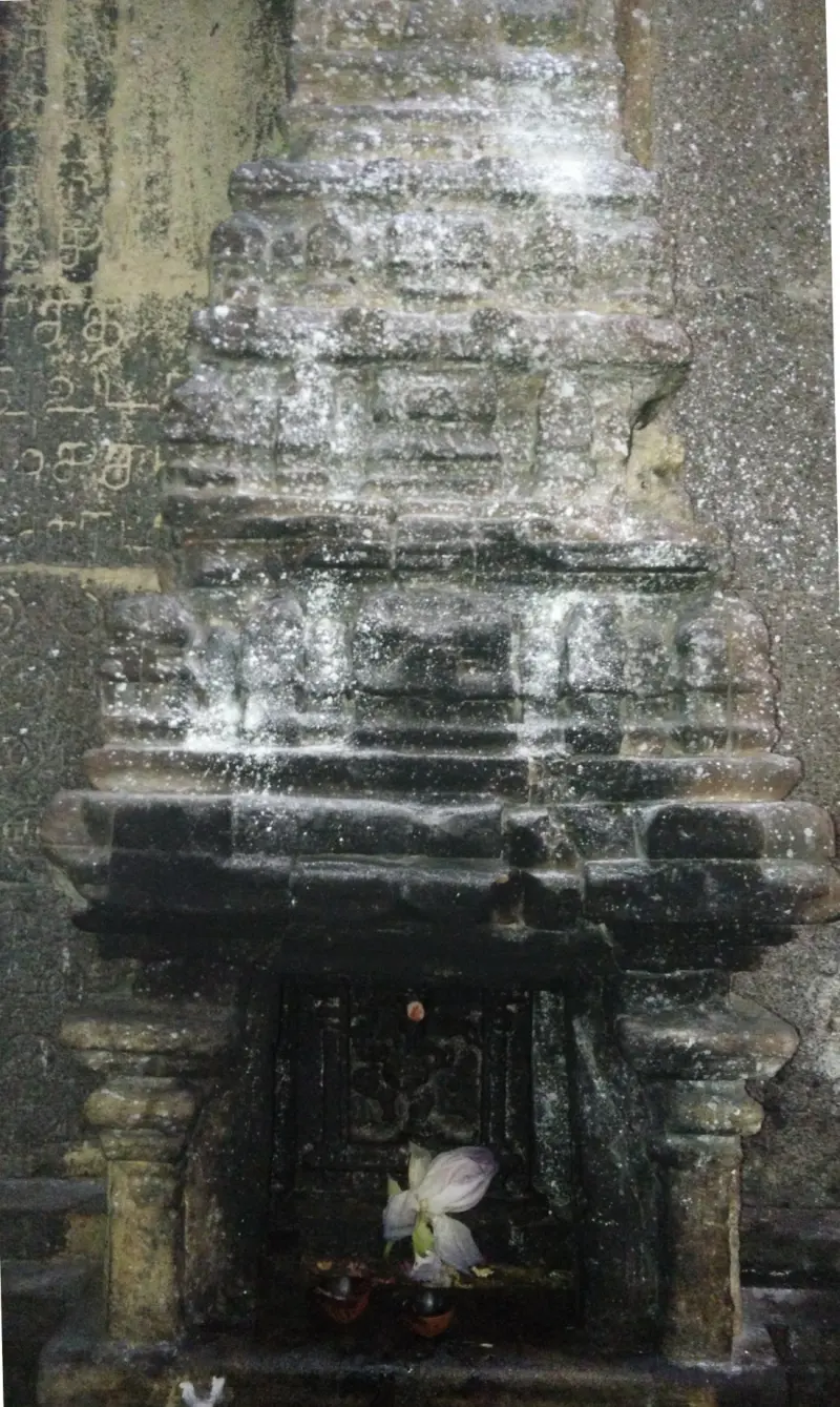 A stone relief in the wall shaped like a small tower, with a flower at its base