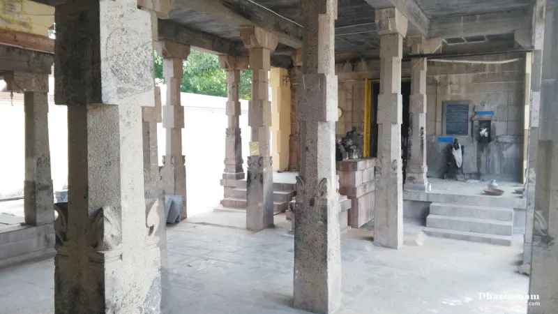 Rows of square stone pillars in an open hall with a few steps rising to a doorway at the back right