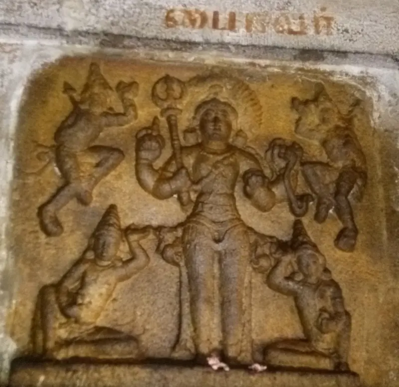 Carved relief of a central standing figure with smaller figures dancing and kneeling around him