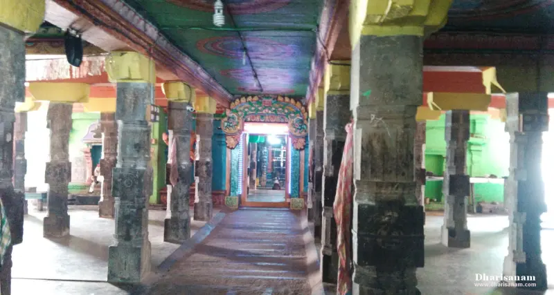 Stone pillars line a corridor leading to a decorated inner doorway