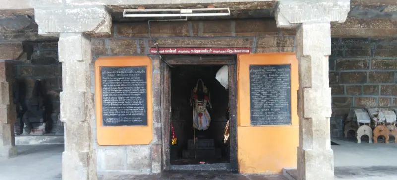 Narrow shrine doorway under a red name board, with an idol inside and a black board on each side