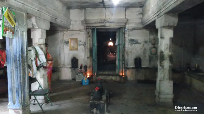 A dim stone hall with a lamp-lit doorway at the far end.