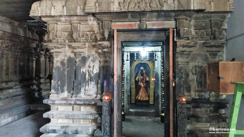 A goddess figure in a gilded arch seen through a stone doorway, with lamps burning