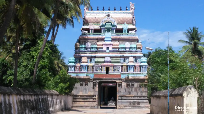 A coloured gateway tower on a plain granite base, seen from the front along a walled path