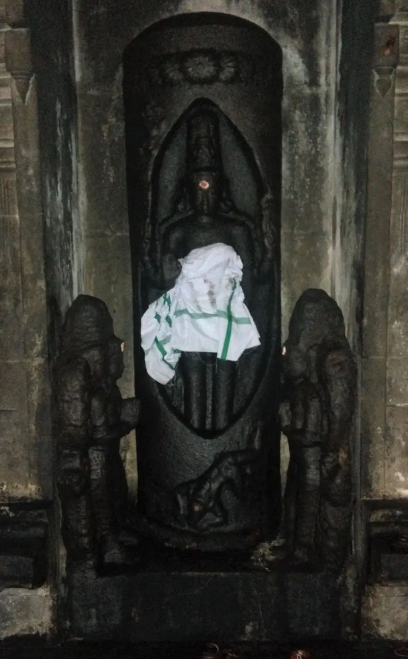 A figure carved inside an upright oval, with a smaller figure on each side