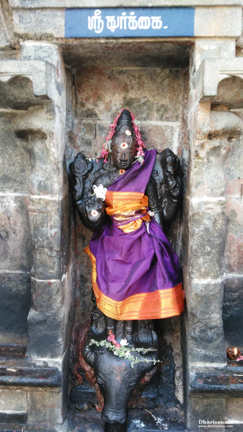 Durgai idol in purple silk standing on a buffalo in a stone niche