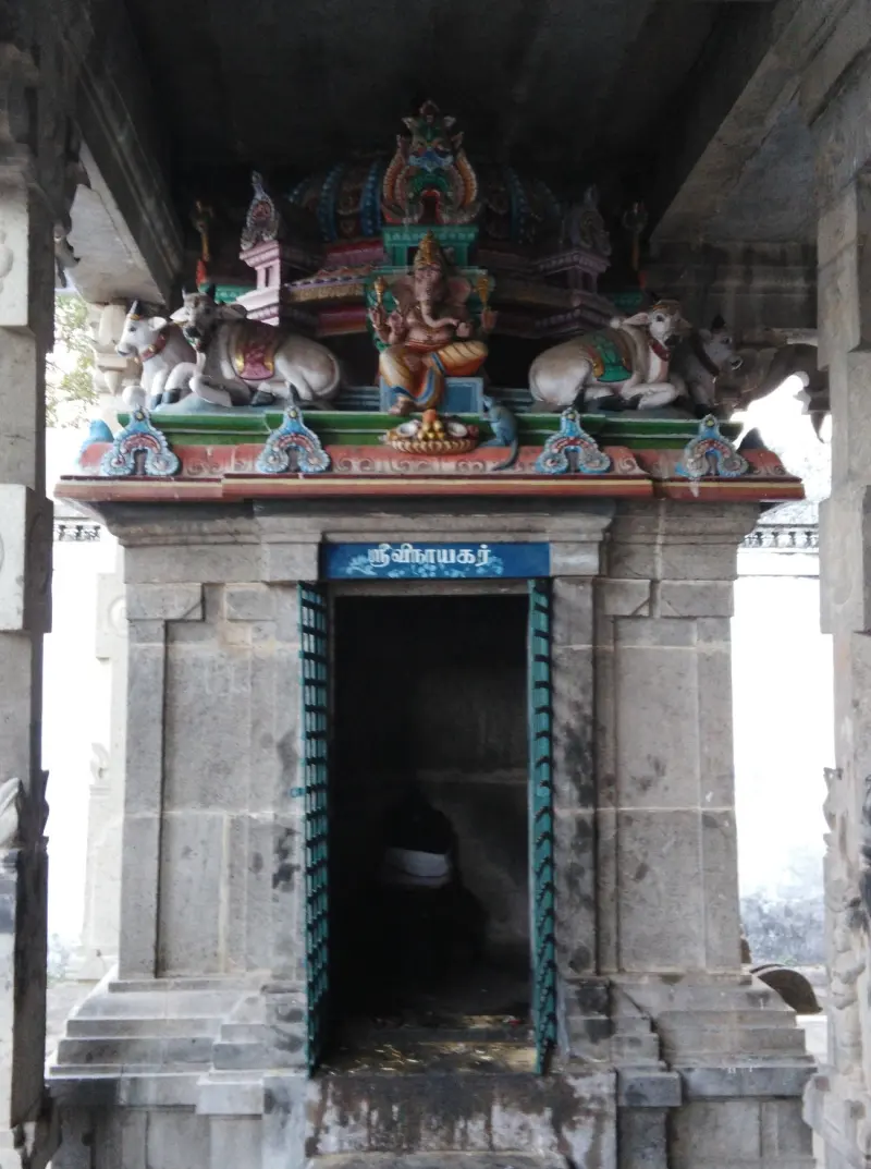 Small stone shrine topped by a painted Ganesha and two bulls, with a name board