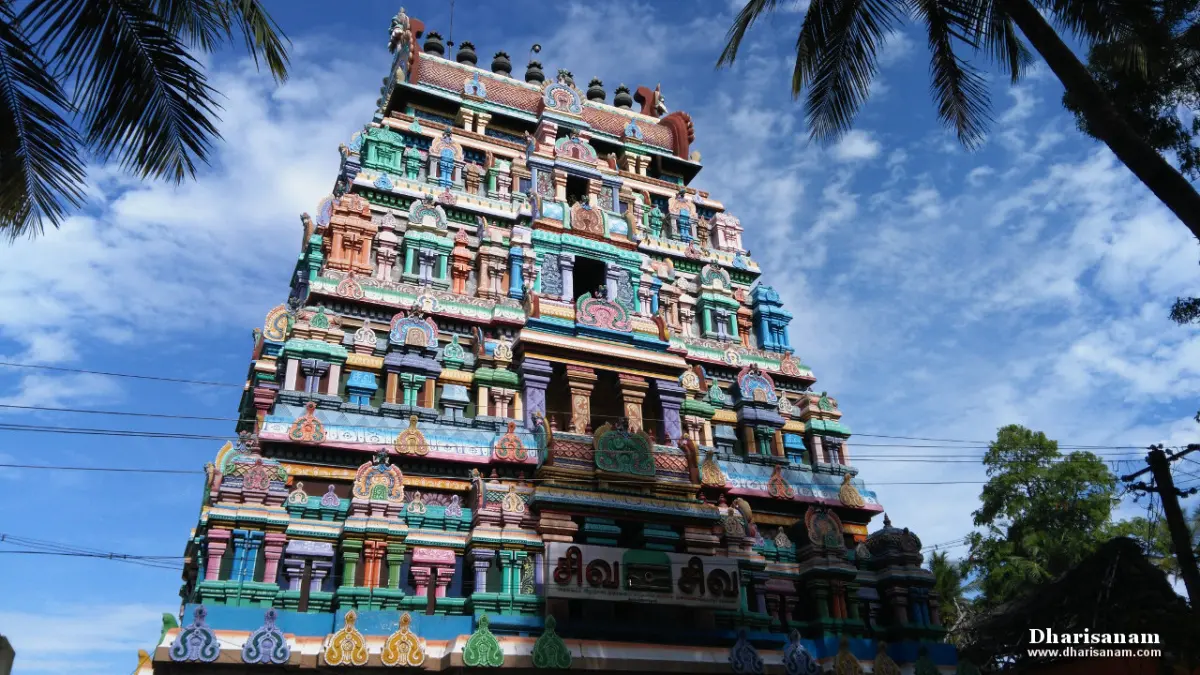 Tiered gateway tower covered in colourful figures, with palm fronds against a blue sky