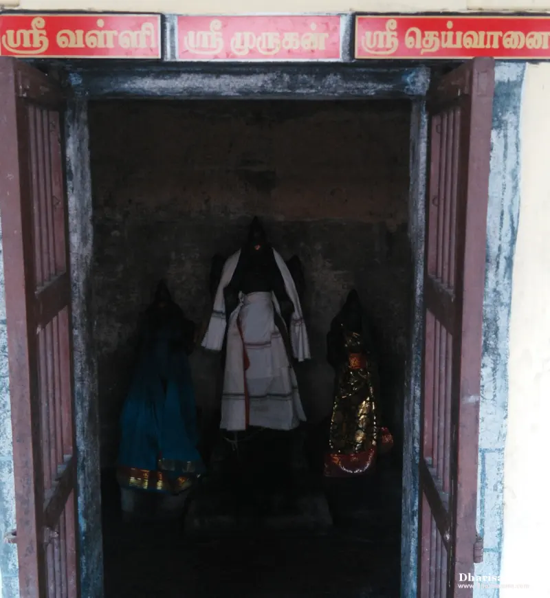Three idols in a dark shrine under Valli, Murugan and Deivayanai boards