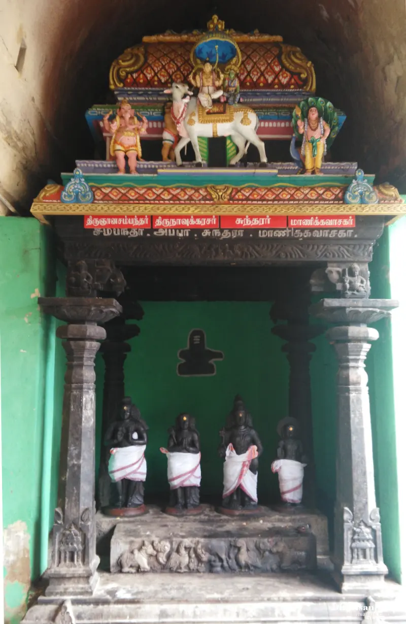 Four dark idols in white cloth in a pillared shrine, with four name plates above