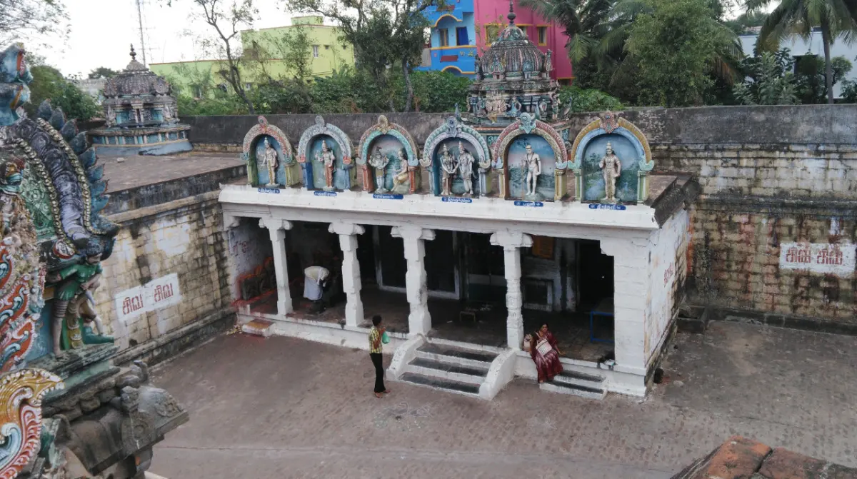 Pillared hall with six painted niches above it, seen from above, with a few visitors on the steps