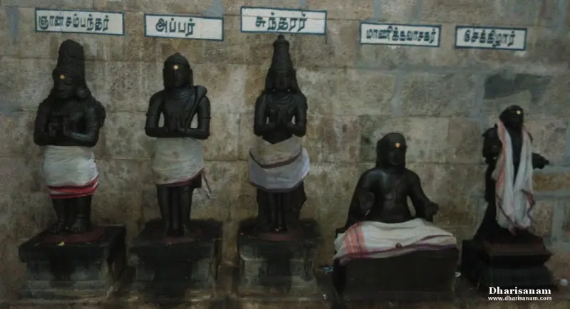 Five black stone idols in a row against a wall, each under a Tamil name board