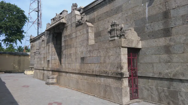 Long granite wall with niches and a red grill gate