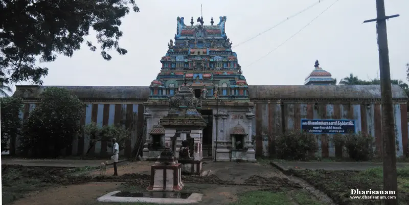 Colourful tower over the entrance of a long wall, with small stone shrines and a tank in front