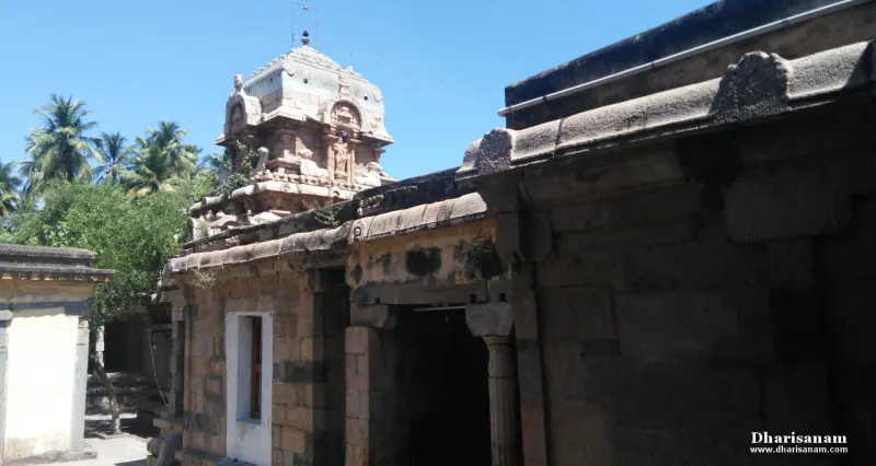 The stone sanctum tower seen over the roofs of the corridor, with palm trees in the distance