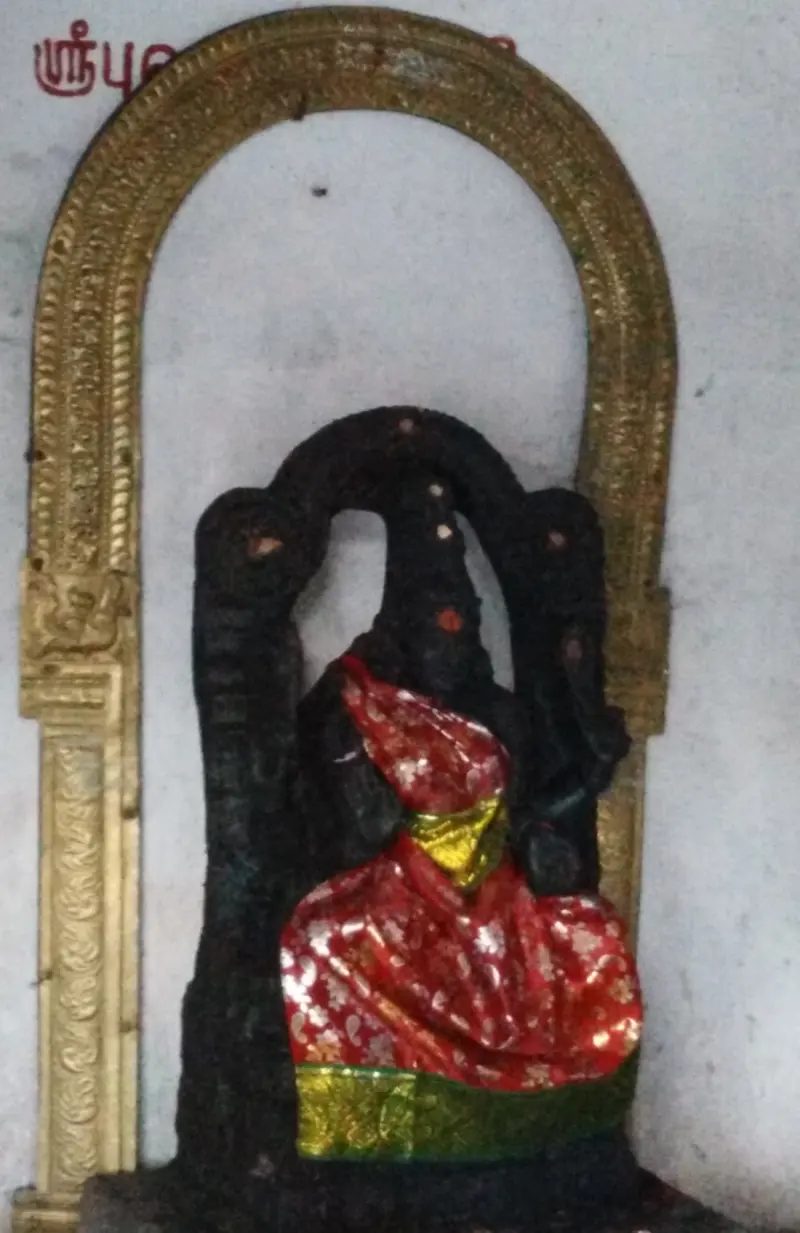 Dark stone figure in red and green silk under a gold-coloured arch