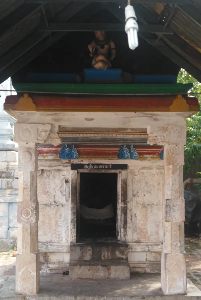 A small stone shrine with an open doorway and a name board above it