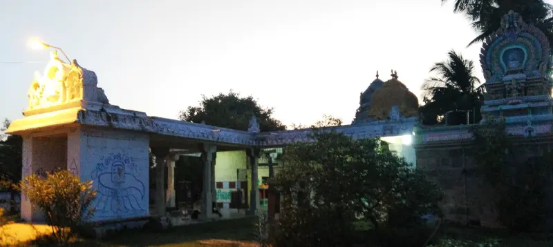 A white entrance porch with sculptures on its roof, a painted design on its wall and a coloured tower on the right.