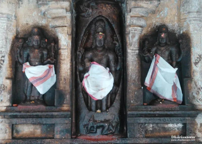 Three stone figures in side-by-side niches, each with a white cloth at the waist