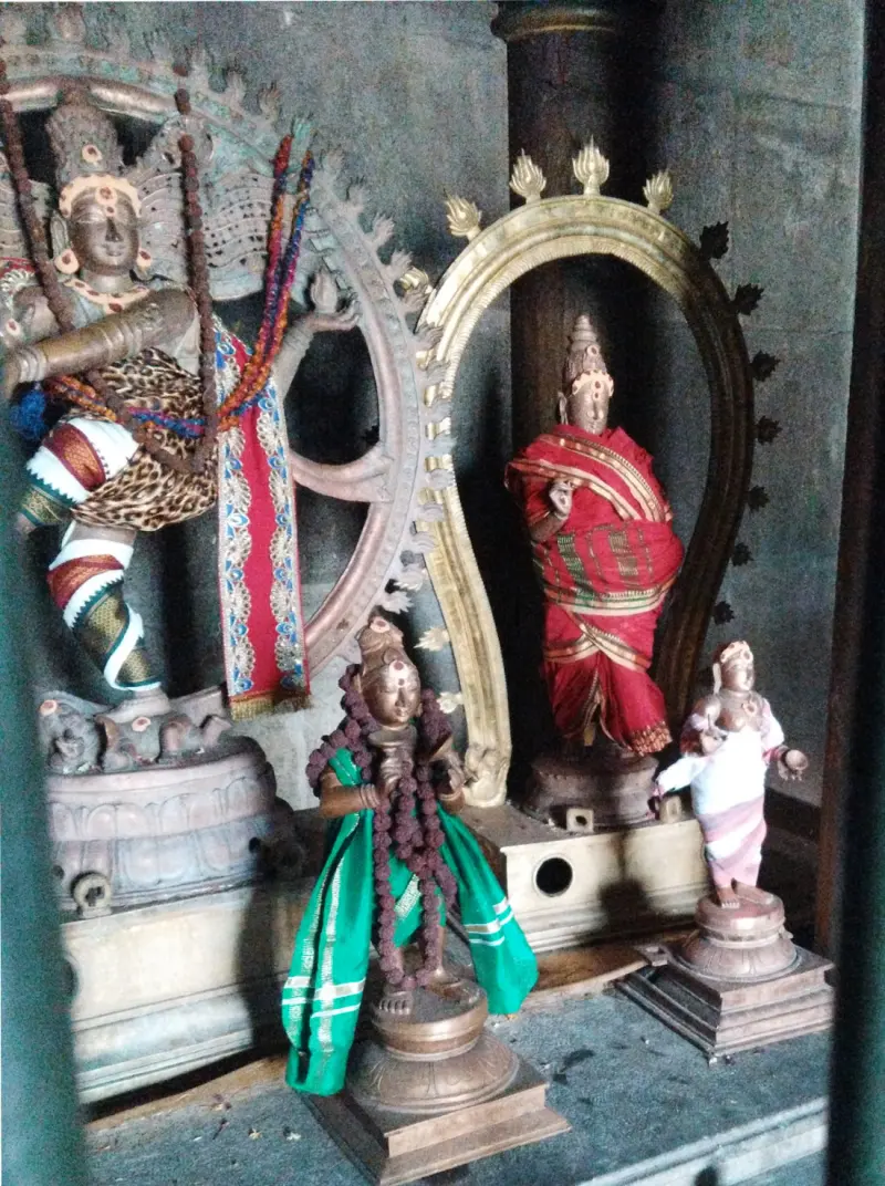 Bronze images of a dancing Natarajar and robed standing figures inside a shrine