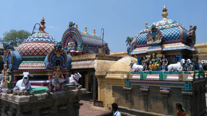 Close view of painted shrine domes with white bulls and small figures, beside a yellow rounded roof