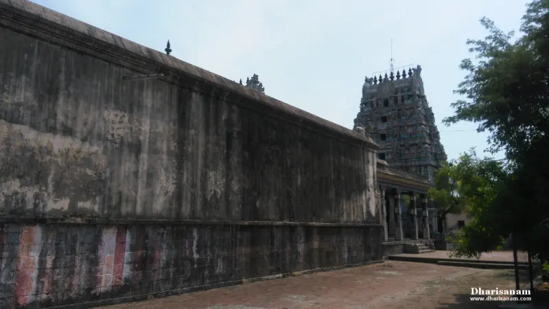A tall weathered stone wall with a tower rising beyond it