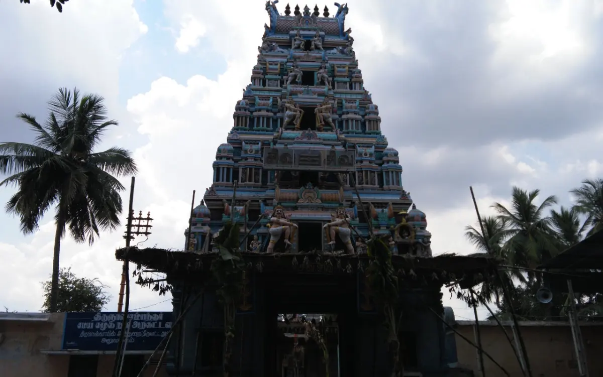 Colourful temple tower rising above an arched entrance, with palm trees on both sides