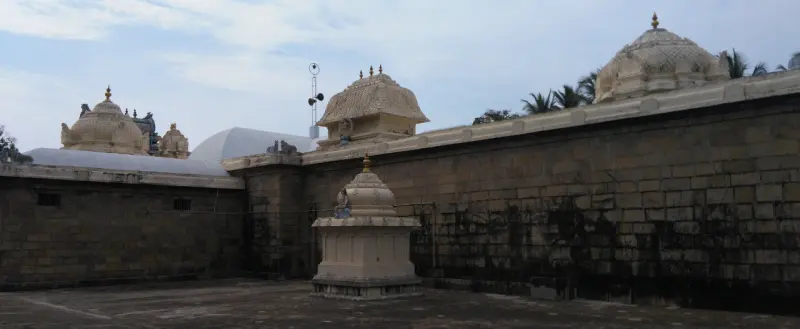 Several small domes rise above a long stone wall, seen from the courtyard