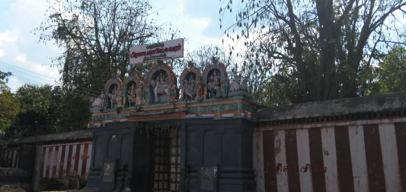 Entrance with painted figures above, a name board, and a compound wall in red and white stripes
